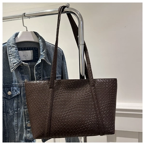 Detailed close-up of dark brown woven texture on large faux leather tote bag