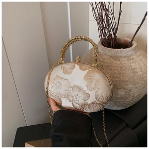 Detail of champagne satin evening clutch with floral embroidery and gold metal handle