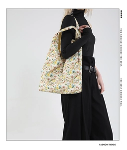 Floral bear print tote bag shown on model with casual minimalist black outfit