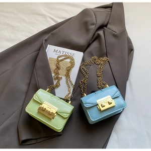 Détail de mini sacs carrés à chaîne en vert pastel et bleu avec boucles dorées