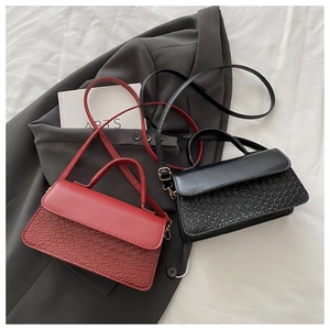 Detail of red and black textured handbags on a grey blazer for a stylish look