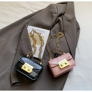 Détail de mini sacs bandoulière roses et noirs avec chaîne dorée et fermoir en métal