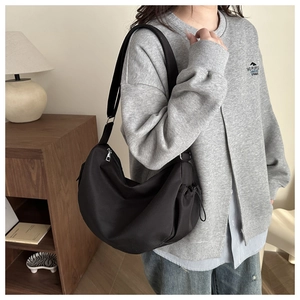Détail du sac croissant en nylon noir porté à l'épaule dans un cadre décontracté