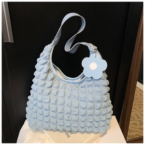 Detail of light blue bubble texture tote bag with a floral charm on a minimal background