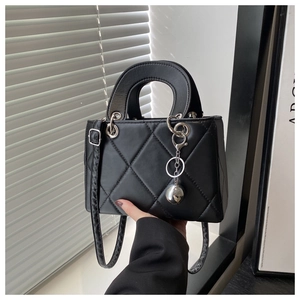 Detail of black quilted leather handbag with silver sphere charm and round handles