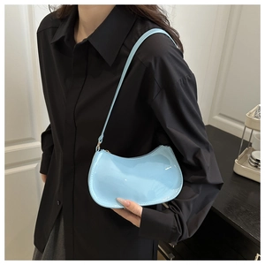 Close-up of a light blue patent leather crescent bag on a model in a black shirt
