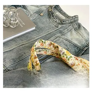 Detail of denim bag featuring 3D floral bear embroidery and metal button accents