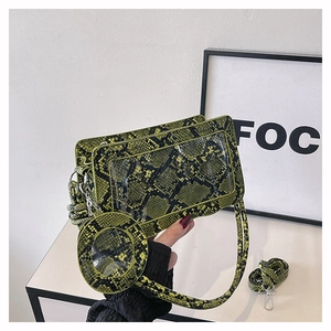 Detail of neon green snakeskin faux leather shoulder bag with a round charm purse