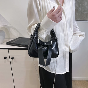 Fashionable black glossy dumpling bag with large bow and silver chain strap for women
