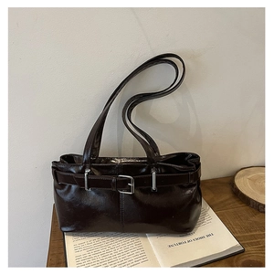 Dettaglio della borsa in pelle marrone scuro con fibbia in argento su libri vintage