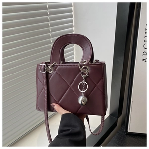 Macro detail of wine red quilted handbag with glossy finish and silver metal charms