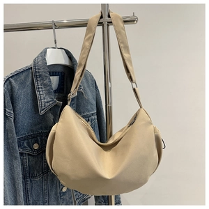 Détail du sac cabas demi-lune en toile beige avec bandoulière large et fermeture éclair
