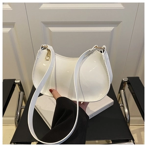 Close-up of white patent leather crescent bag with golden zipper on a black chair
