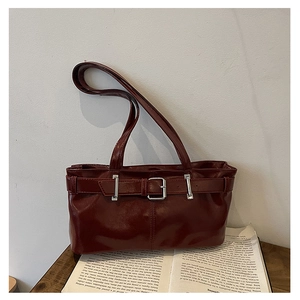 Dettaglio borsa a spalla bordeaux vintage con fibbia d'argento su libri aperti
