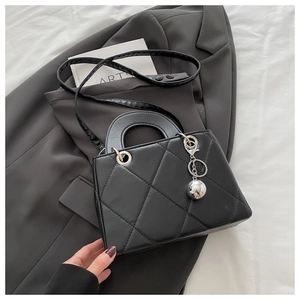 Close-up of black quilted leather stitching detail and silver ball charm accessory