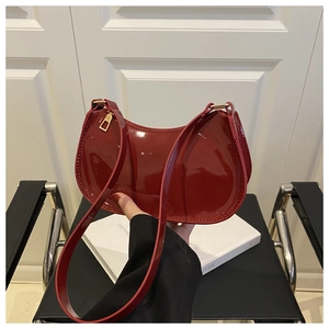 Detail of red patent leather hobo bag with glossy finish and golden hardware zippers