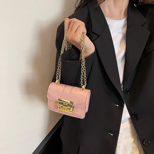 Mini sac bandoulière rose avec chaîne dorée et fermoir sur un blazer noir chic