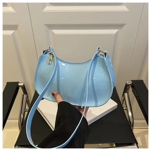 Close-up of light blue patent leather shoulder bag featuring a sleek crescent moon shape