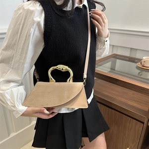 Minimalist beige crossbody bag with a curved gold metal handle and textured patchwork
