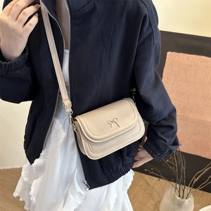 Fashionable apricot flap crossbody bag with metal bow detail on a leather texture