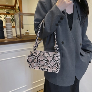 Snake pattern handbag with wavy edges and round pouch accessory on a shoulder strap