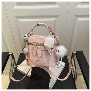 Détail du sac boîte rose avec poignée en foulard de soie et pendentif peluche blanc