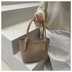 Détail d'un sac seau en similicuir kaki avec coutures verticales et boucle dorée