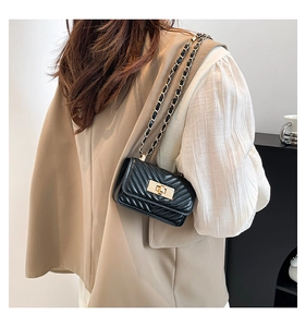 Detail of a black quilted leather mini chain bag with a gold rectangular metal turn-lock