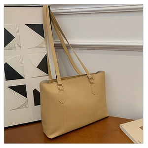 Détail du sac cabas beige avec anneaux en métal doré et coutures décoratives fines