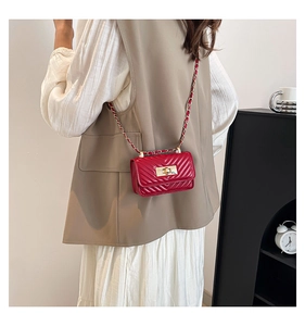 Detail of red quilted mini crossbody bag with V-stitch design and gold twist lock