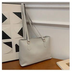 Détail du sac cabas en cuir gris clair avec coutures fines et boucles en or rose poli