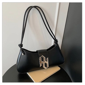 Detail of minimalist black underarm bag featuring a metallic logo buckle and dual straps