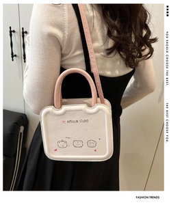 Detailed view of white biscuit bag with pink handle and bear pattern worn on shoulder