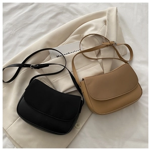 Close-up of minimalist black and beige leather shoulder bags on soft fabric background