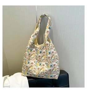 Detail of 3D teddy bear and flower patches on a cream shoulder tote bag texture
