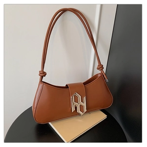 Detailed close-up of brown leather bag with geometric silver H-buckle and knotted straps