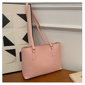 Détail du sac cabas en similicuir rose pâle avec boucles dorées et coutures de précision
