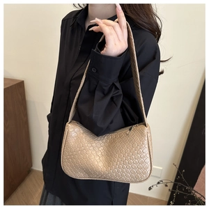 Detail of beige woven shoulder bag featuring textured interlaced pattern and gold zipper