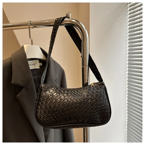 Detail of woven texture on a black hobo bag hanging on a metal rack with a blazer