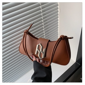 Detailed shot of brown crescent underarm bag with gold geometric buckle and knotted strap