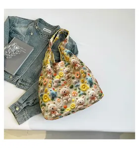 Detail of yellow tote bag with 3D crochet flowers and bears on textured fabric