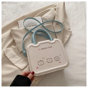Détail du sac bandoulière crème avec motifs dessins animés et anses bleu clair sur veste