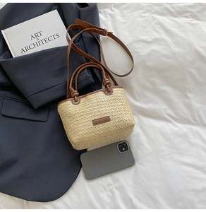 Vista dettagliata della mini borsa in paglia con manici in pelle e cellulare per dimensioni