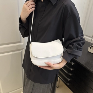 Minimalist white leather saddle bag for women with flap closure and slim shoulder strap
