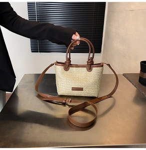 Dettaglio della borsa a secchiello in paglia estiva con finiture in pelle marrone