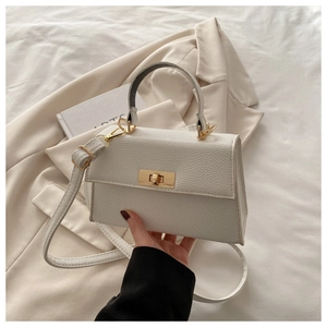 Detail of white lychee pattern handbag with gold turn-lock and adjustable shoulder strap