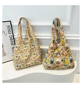 Detailed macro view of 3D crochet flowers and bear designs on a beige knitted tote bag