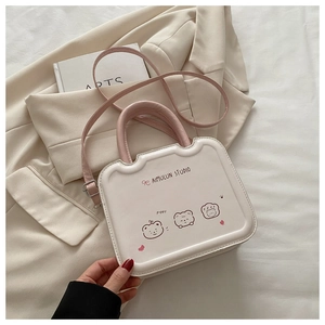 Détail du sac bandoulière beige chic avec imprimés d'ours et poignée rose sur un blazer