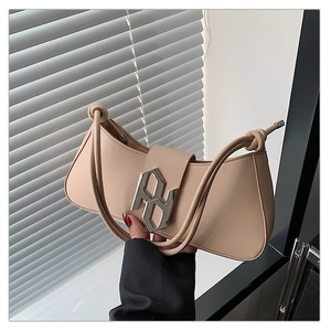 Detail of beige leather bag with a large silver metal buckle and decorative knot