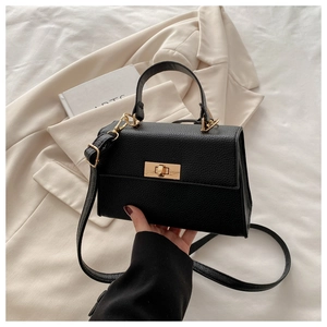 Detail of black pebble grain leather handbag with gold twist lock and a single top handle